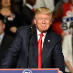 A man at a podium smiling during a rally.