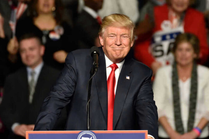 A man at a podium smiling during a rally.