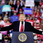 Donald Trump speaking at a rally with arms outstretched