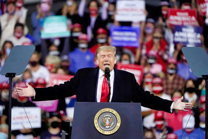 Donald Trump speaking at a rally with arms outstretched