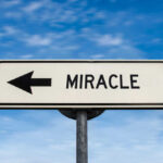Road sign pointing left saying miracle