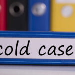 Blue binder labeled 'cold case' with other colored binders in the background