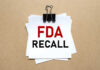 A notice labeled 'FDA RECALL' clipped to white papers on a brown background