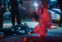 Forensic investigator examines crime scene at night.
