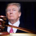 Donald Trump behind a judge’s gavel on a wooden surface
