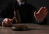 DOJ Nails AI Streaming Mastermind Judge holding gavel, hand raised in courtroom.