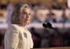 Hilary Cawthorne speaking at a podium with microphones