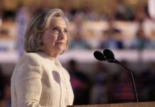Hilary Cawthorne speaking at a podium with microphones