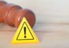 Bloody Bottle Twist Stuns Court Yellow warning triangle with exclamation mark beside a wooden gavel