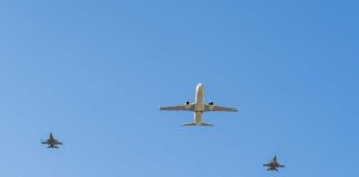 A commercial airplane flying above two military jets in a clear blue sky