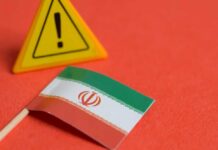 Iran Scheme Hits US Base Iranian flag next to a caution sign on a red background