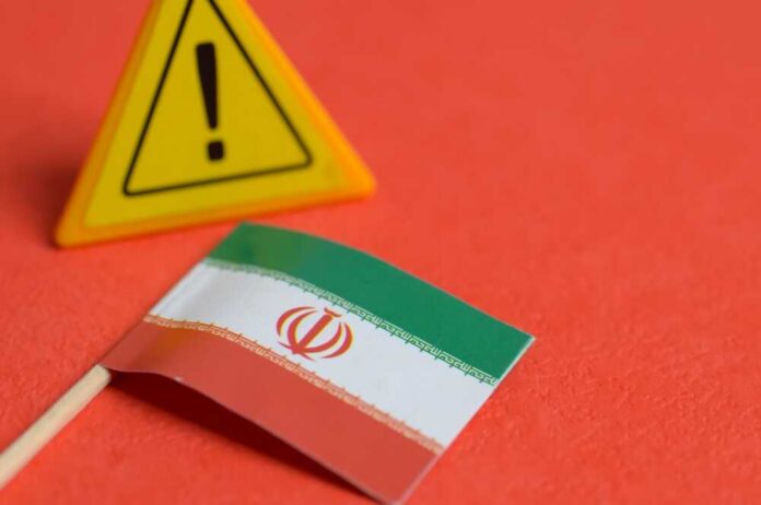 Geopolitical,Warning,Concept,With,Iran,Flag,And,Triangular,Exclamation,Sign Iranian flag next to a caution sign on a red background