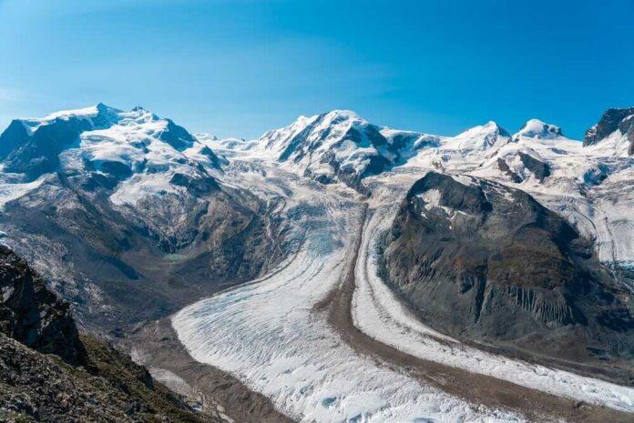 Panoramic,View,Of,The,Gorner,Glacier,With,Monte,Rosa,And Glacier winding through snow-capped alpine mountains under a clear blue sky