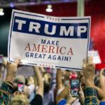 Large crowd holding Trump Make America Great Again sign.