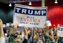Trump Storms Choctaw Land – Why Here? Large crowd holding Trump Make America Great Again sign.